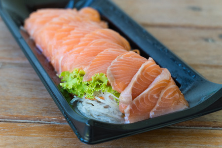 Salmon in black plate on wooden tableの写真素材