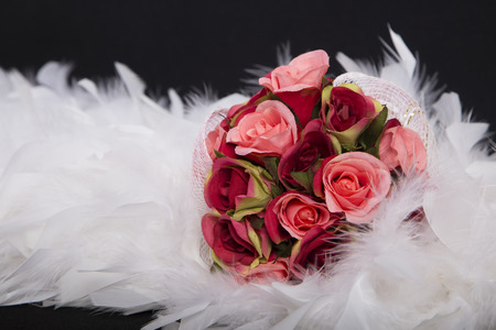 selective focus with a bouquet of red roses shade on white feather, beautiful Artificial flower sweet love on valentine or the anniversary day on black background, has copy spaceの写真素材