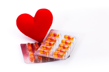 Red heart and Vitamin in capsules on white background with concept about Health careの写真素材