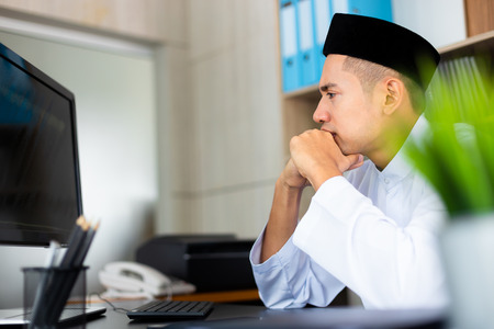 Young handsome muslim businessman working with computer at the office, He looking a large monitor