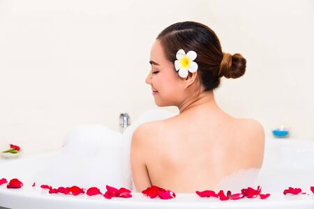 Young beautiful woman enjoying in bathtub with mineral water and soap bubbleat spa salon,の写真素材