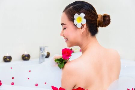 Young beautiful woman enjoying in bathtub with mineral water and soap bubbleat spa salon,