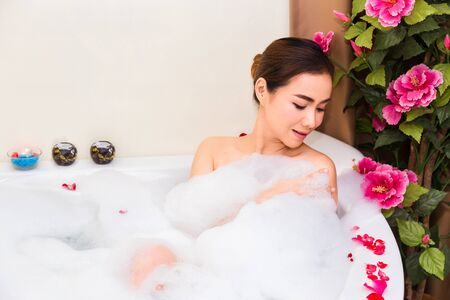 Young beautiful woman enjoying in bathtub with mineral water and soap bubbleat spa salon,