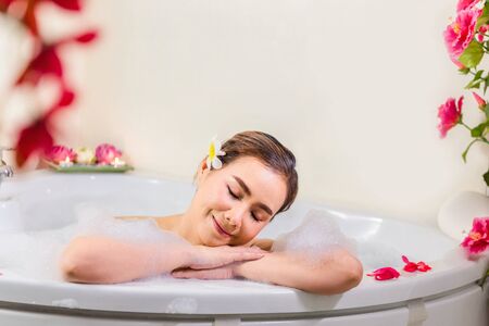 Young beautiful woman enjoying in bathtub with mineral water and soap bubbleat spa salon,の写真素材
