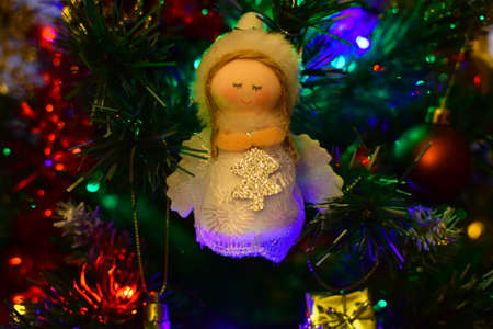 Christmas toy angel on a Christmas tree decorated with a garlandの写真素材