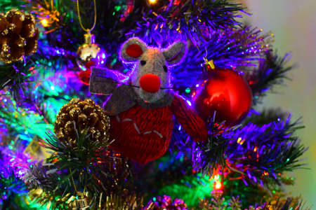Christmas toy rat on a Christmas tree decorated with a garlandの写真素材