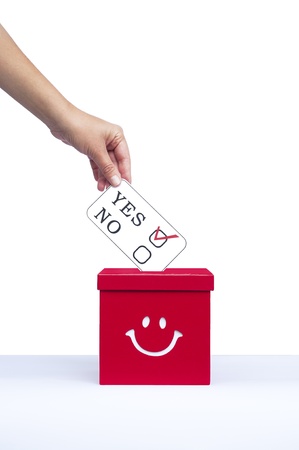 Hand putting a voting ballot in a slot of boxの写真素材