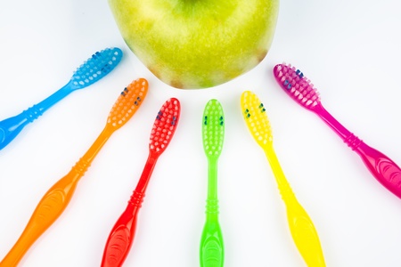 Six colorful toothbrushes and an appleの写真素材
