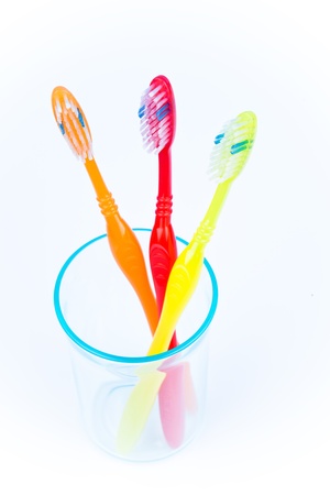 Three colorful toothbrushes in a water glassの写真素材