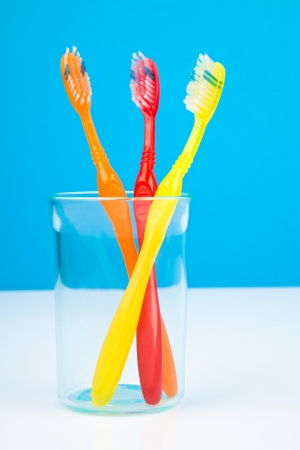 Three colorful toothbrushes in a water glassの写真素材