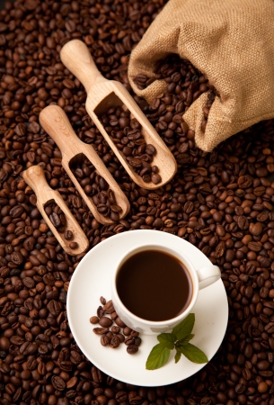 Wooden shovels full of coffee with burlap sack and a cup of coffeeの写真素材