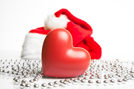 A gift box and a ceramic heart standing next to Santa Claus red hat の写真素材