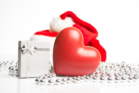 A gift box and a ceramic heart standing next to Santa Claus red hat の写真素材