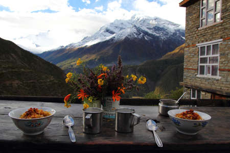 Breakfast in the mountains - detail of two bowls, flowers,cups, with a view on the mountainsの写真素材