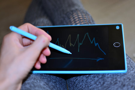 Woman is holding drawing board on her knees and drawing line chartsの写真素材