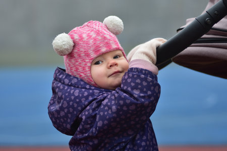 Baby girl is walking in sports field in winter autumn.Outdoors activities fun time outside. Kid in...