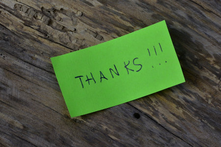 Message thanks thank you on green sticky note day on wooden board textured background