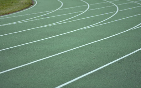 Green running track with white lines. Footpath in right side and green grass in left side.の写真素材