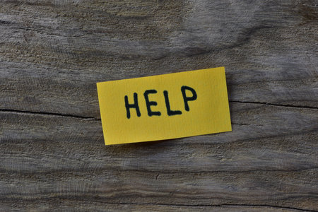 Message help on yellow sticky note on wooden board textured background. Black marker wrote word help...