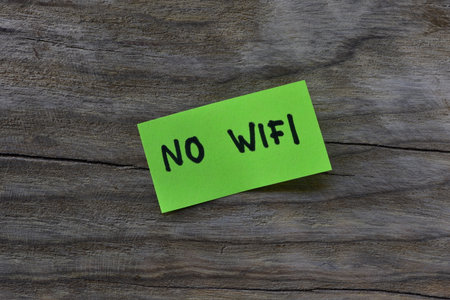 Message no wifi on green sticky note on wooden board textured background. Black marker wrote words no wifi on note paper.の写真素材