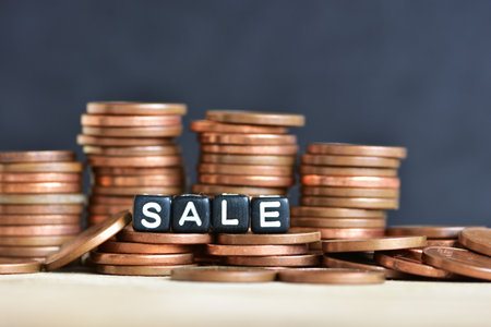 Stacked coins into columns on wooden background and word sale made of plastic beads. concept of money economics sale shops idea copy spaceの写真素材