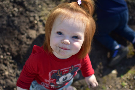Baby girl is looking up and smiling in a back yard in spring.の写真素材