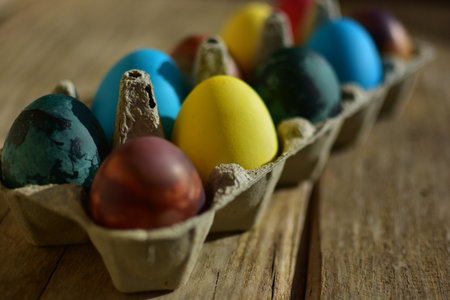 Colorful easter eggs in a paper box decoration on cracked wooden background. Traditional european...