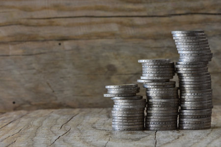 Stacked coins into three ascending columns on wooden background concept of money economics copy...