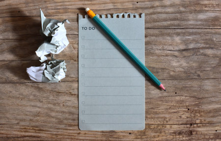 To do list blank note paper and a pencil on wooden background. Crumpled sheet of paper at the side. Work list top view empty note book page on wooden table. Copy space simple minimal organizer concept.の写真素材