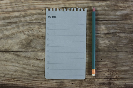 To do list blank note paper and a pencil on wooden background. Work list top view empty note book page on wooden table. Copy space simple minimal organizer concept.の写真素材