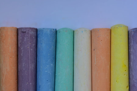 Vertical arrangement of colorful pastel chalk sticks in soft hues. Symmetrical pattern and vibrant...