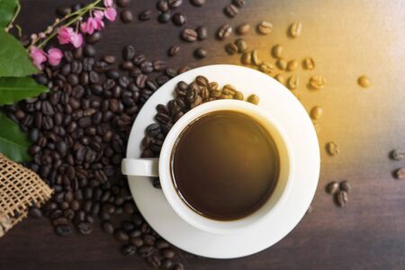 Black coffee cup with beans on wooden table.background for your products.focus around a cup of coffee-mage.の写真素材