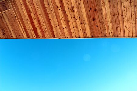 Wooden lower ceiling and blue skyの写真素材
