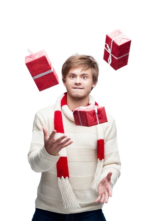 portrait of young funny cheerful caucasian man which juggle red christmas gifts with funny expressionの写真素材