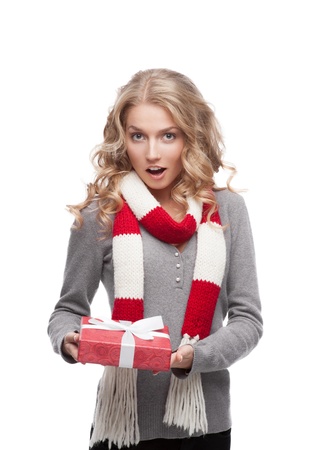 young surprised casual blond woman holding red christmas gift isolated on whiteの写真素材