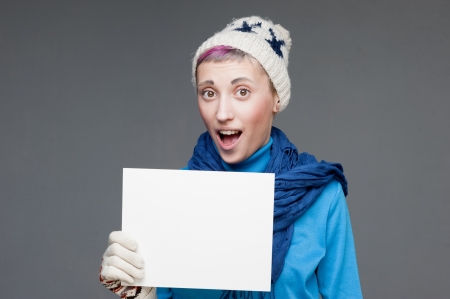 freaky blond caucasian girl in winter clothing holding sign with funny expressionの写真素材