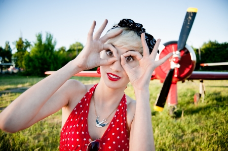 outdoors pin-up portrait of young blond cheerful caucasian woman in red retro dress の写真素材