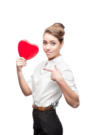 young smiling caucasian brunette business woman holding and pointing at red Valentine heartの写真素材