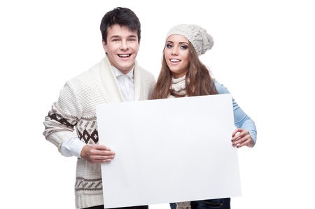 young casual caucasian brunette couple in winter clothing holding big sign and looking at camera with happy smileの写真素材