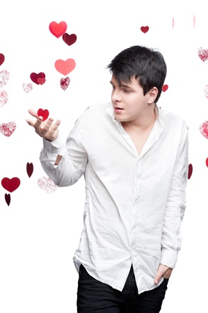 young caucasian brunette man in white shirt standing with gentle expression over red flying hearts on backgroundの写真素材