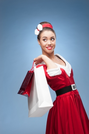 young cheerful retro girl in red vintage dress holding shopping bagsの写真素材