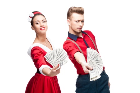 cheerful young caucasian couple in red vintage clothing holding money isolated on whiteの写真素材