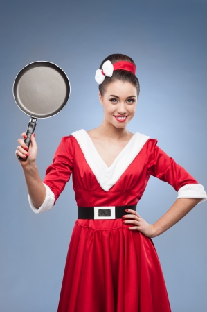 young cheerful retro girl in red vintage dress holding frying panの写真素材
