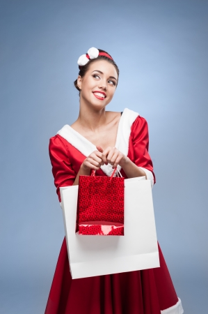 young cheerful retro girl in red vintage dress holding shopping bagsの写真素材