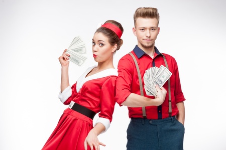 cheerful young caucasian couple in red vintage clothing holding money isolated on whiteの写真素材