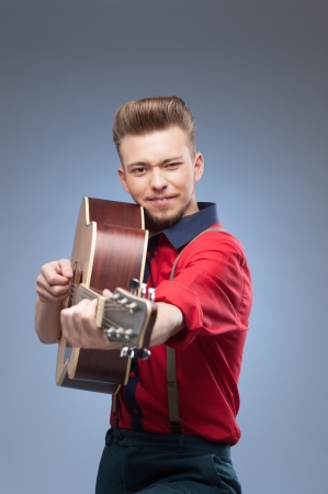 caucasian young vintage man in red shirt playing guitar over blue backgroundの写真素材