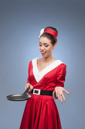 young cheerful retro girl in red vintage dress holding frying panの写真素材