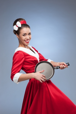 young cheerful retro girl in red vintage dress holding frying panの写真素材