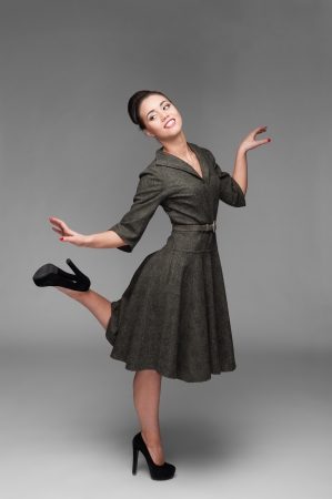 cheerful young caucasian woman in green vintage dress dancing isolated on grayの写真素材