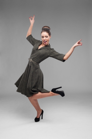 cheerful young caucasian woman in green vintage dress dancing isolated on grayの写真素材